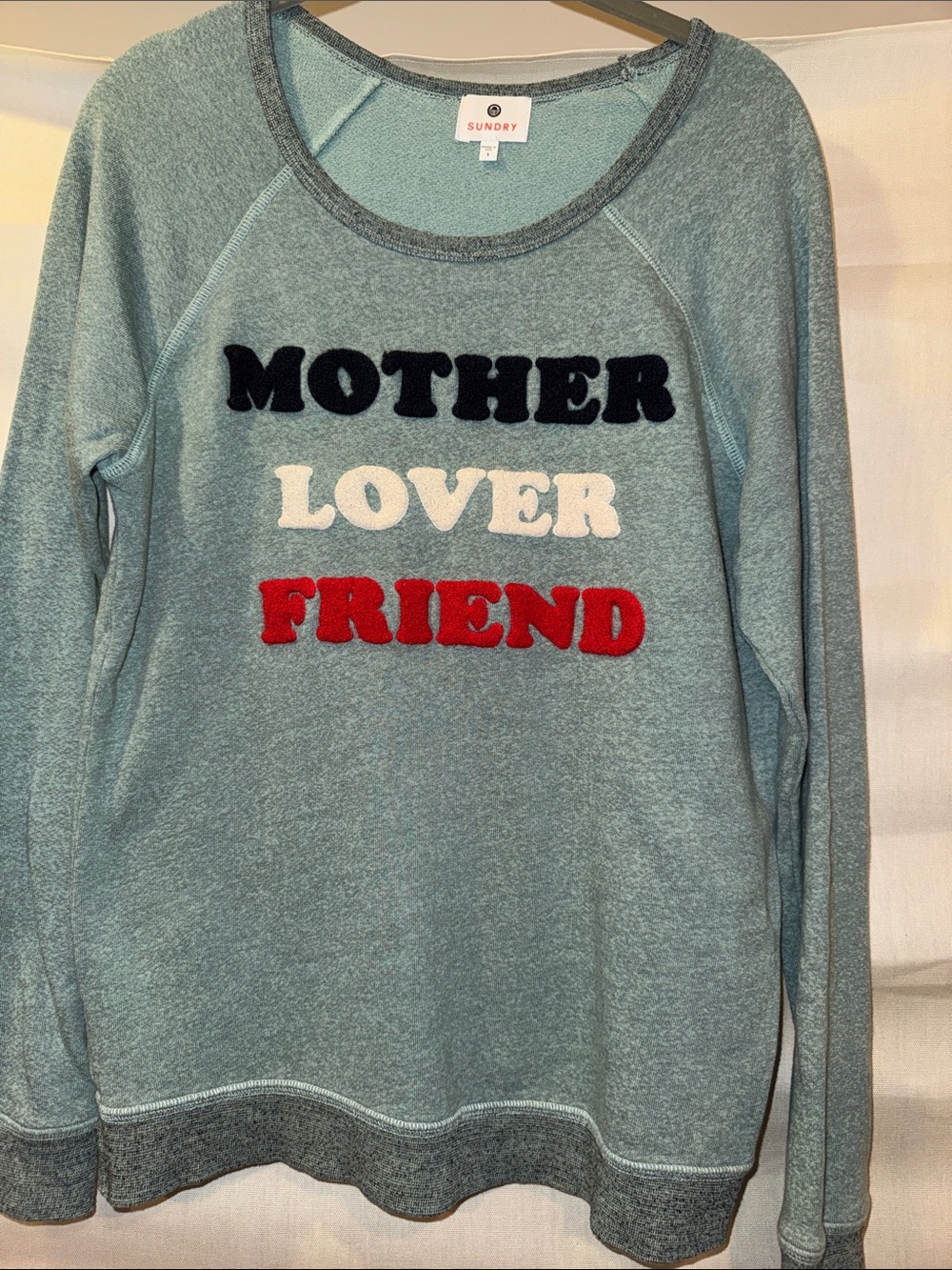 Sundry blue pullover with black, cream & red tufted lettering